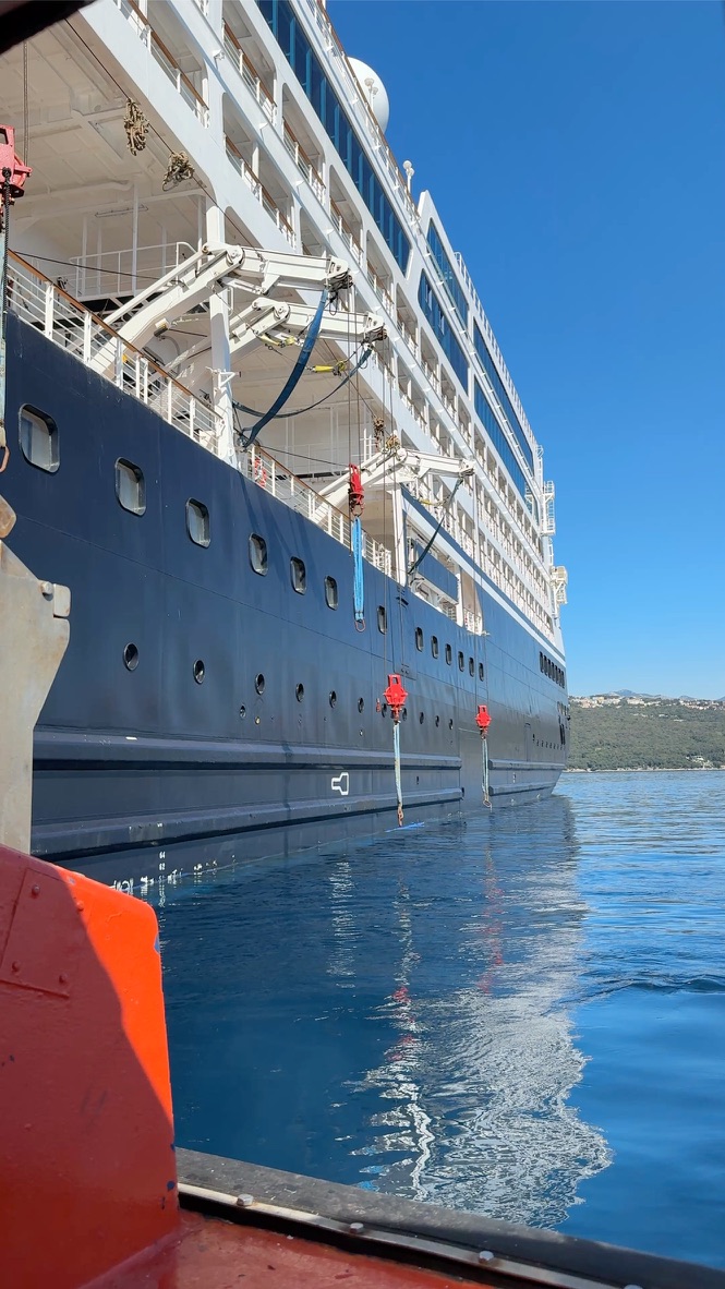 An ocean cruise ship seen from a tender on calm blue water