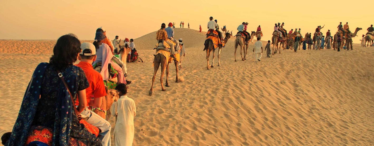 Travelers riding camels across golden desert dunes