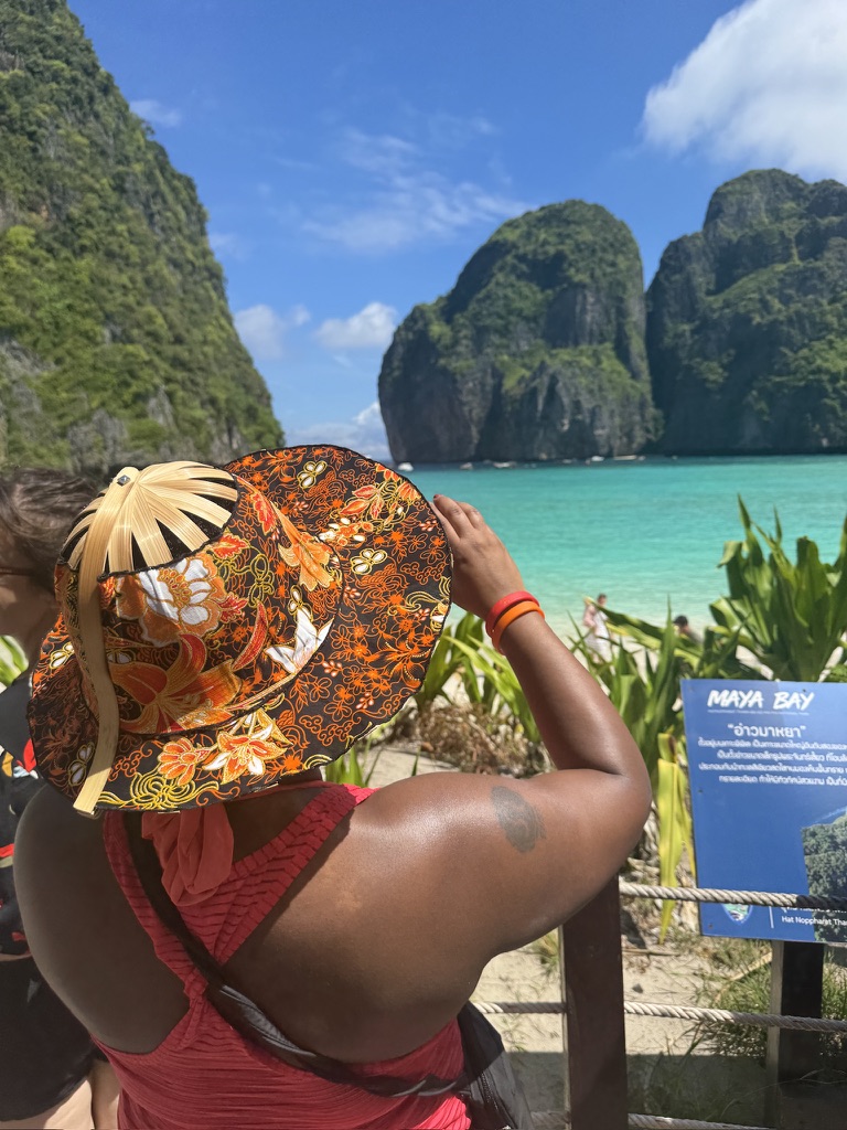 A traveler looking out over turquoise water and limestone cliffs at Maya Bay